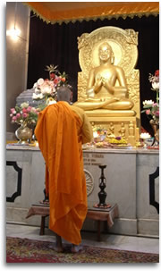 写真：初転法輪の釈尊像に礼拝する比丘（インド・サールナート）